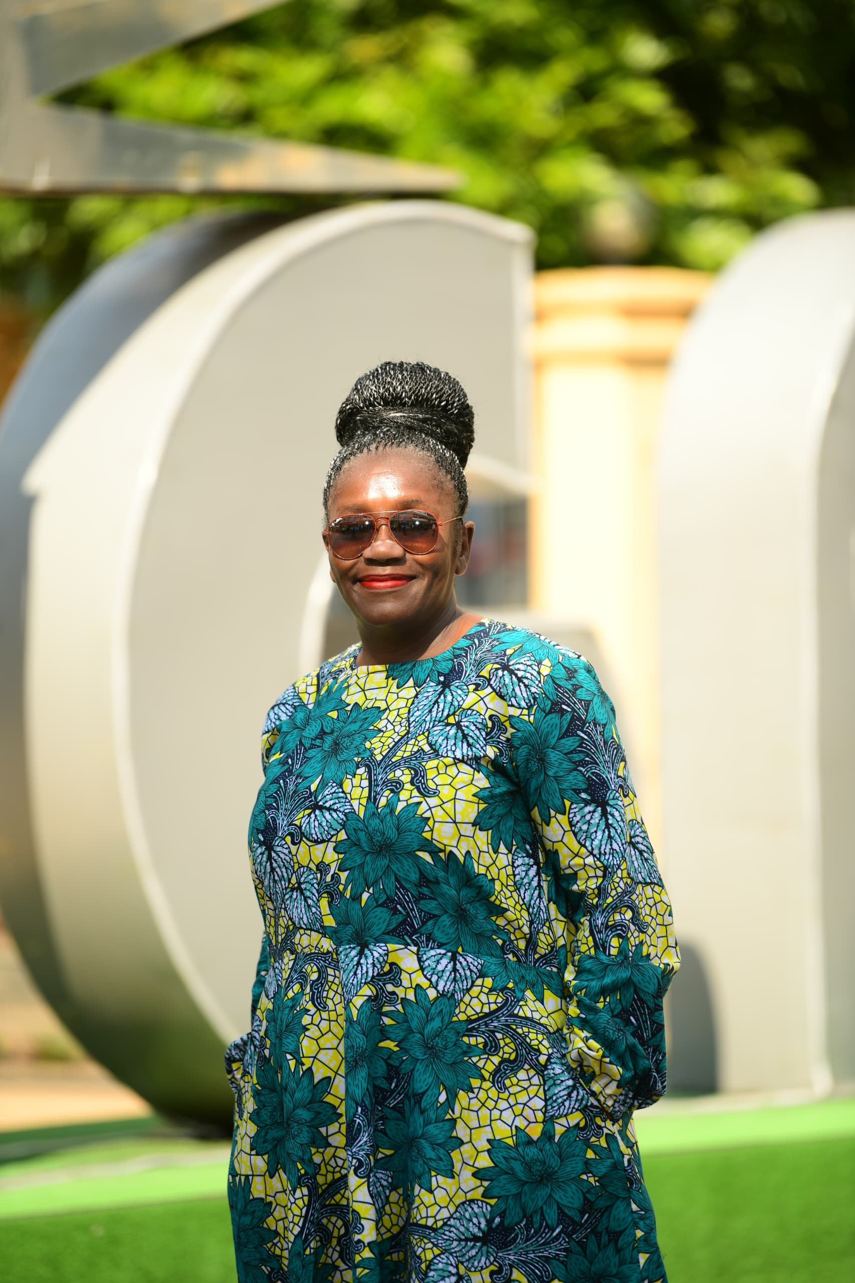 Close-up portrait of Anike smiling in front of the KIGALI sign
