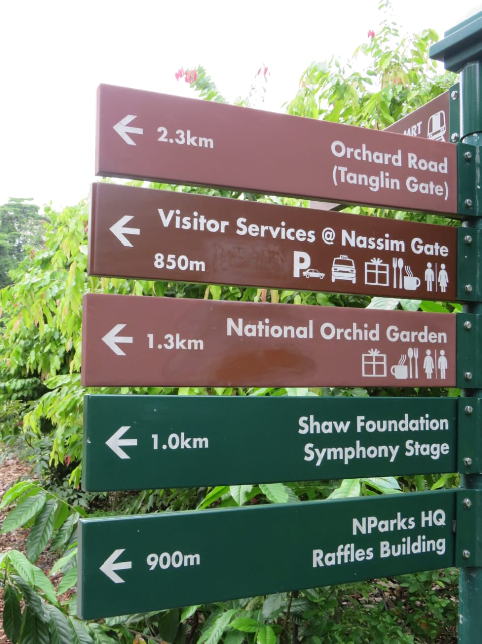 Directional signs pointing to various Singapore attractions including Orchard Road and National Orchid Garden