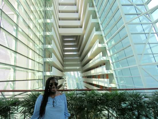 Anike in a modern building with impressive glass architecture and multiple floors