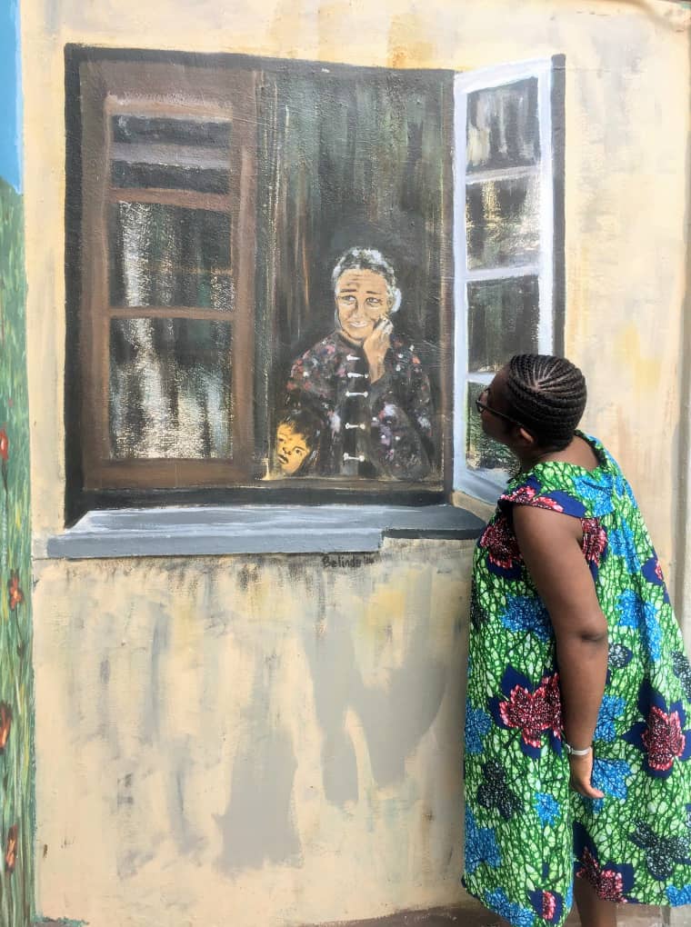 Anike interacting with a 3D mural of a person looking out of a window