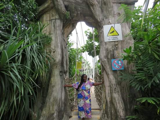 Anike standing in a natural wooden archway in a lush park setting