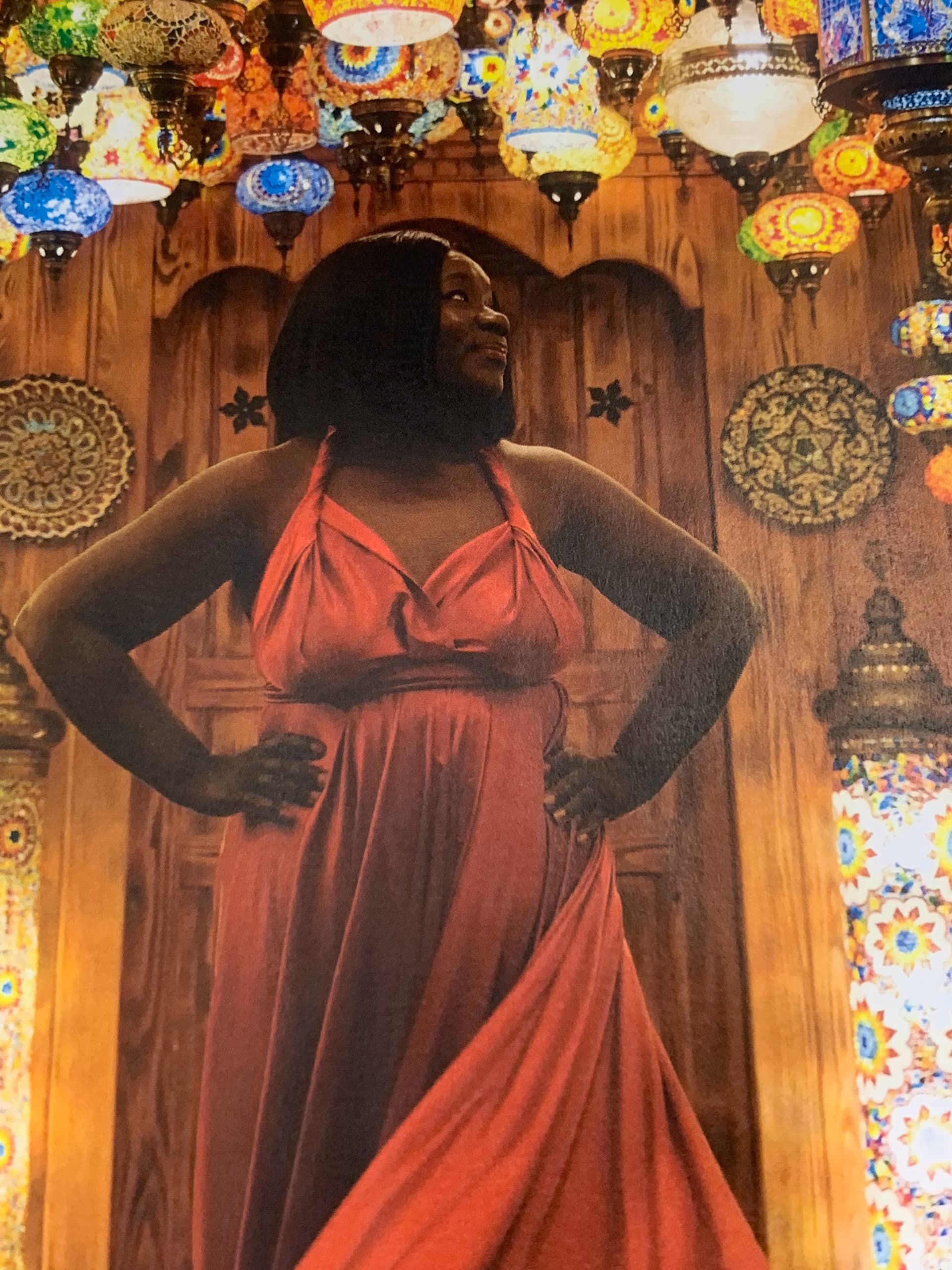 Anike posing confidently in red dress among hanging Turkish lanterns